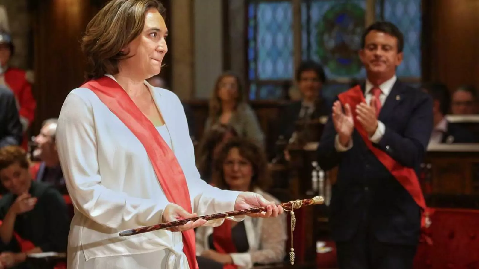 Ada Colau sosté la vara d'alcaldessa després de ser investida. Manuel Valls l'aplaudeix de fons