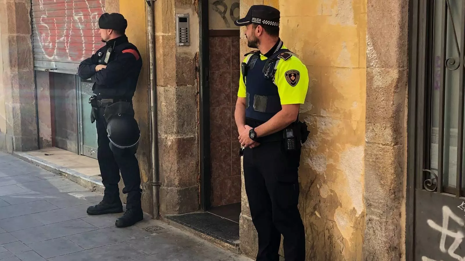 Un agent dels Mossos i un altre de la Guàrdia Urbana, davant del portal de l'edifici on hi havia el narcopis