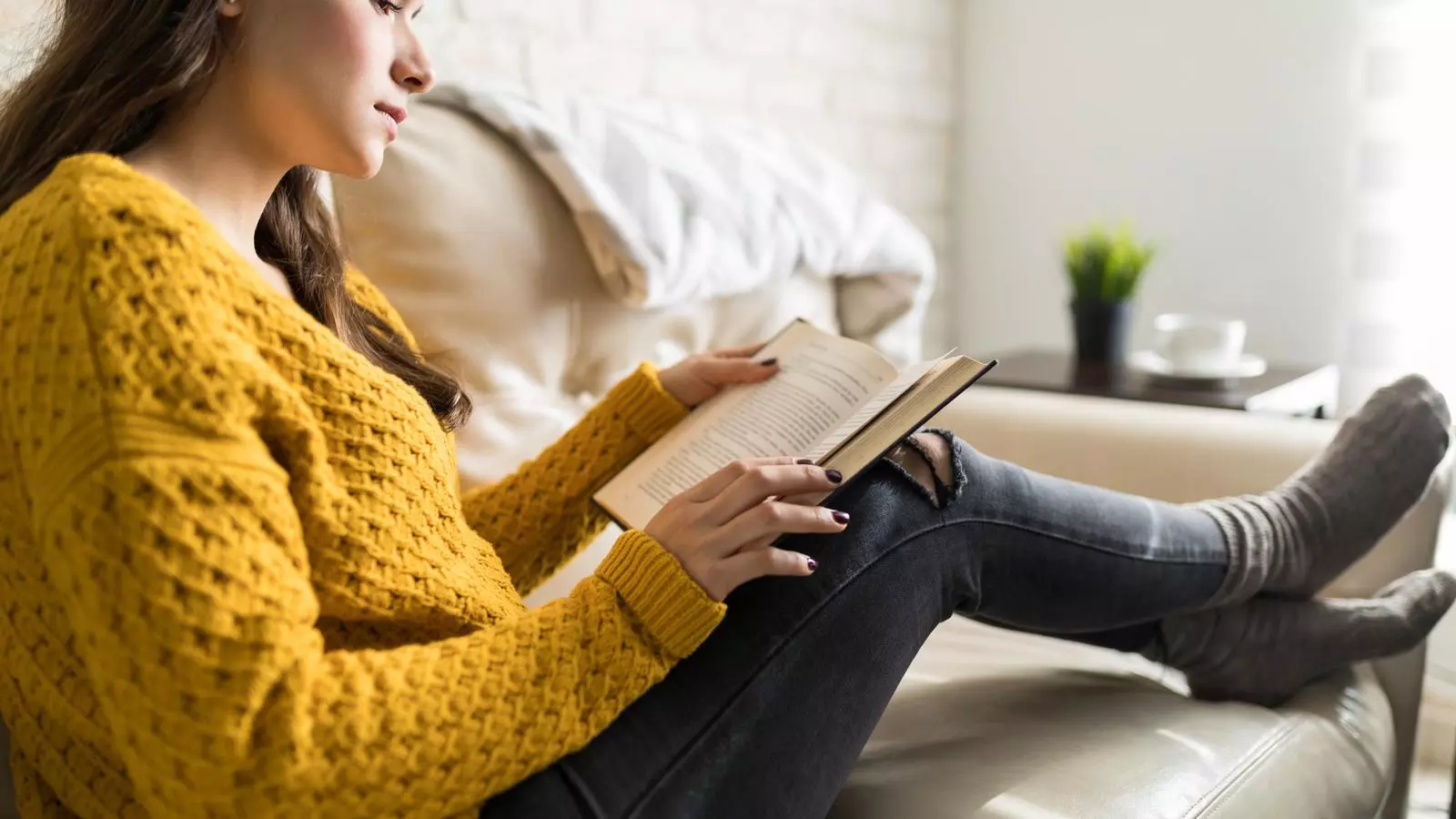 Una noia llegeix un llibre a casa seva