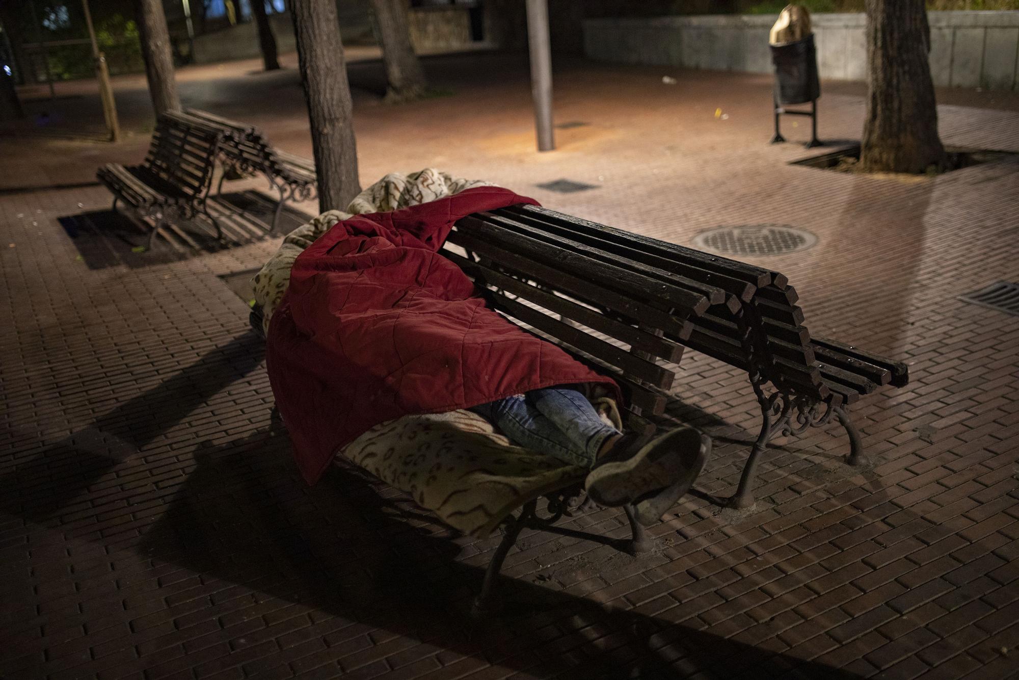 Un sensellar dorm al banc d'una plaça de Santa Coloma de Gramenet.