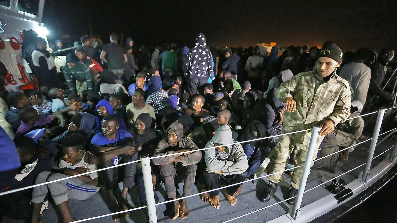 Desenes de migrants arribant a Trípoli a bord d’una patrullera de Líbia.