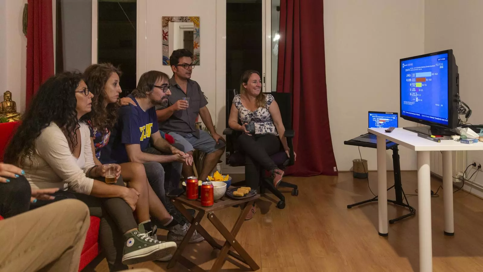 Un grup d'italians residents a Barcelona segueixen el recompte de vots diumenge a la nit en un pis del barri del Raval.