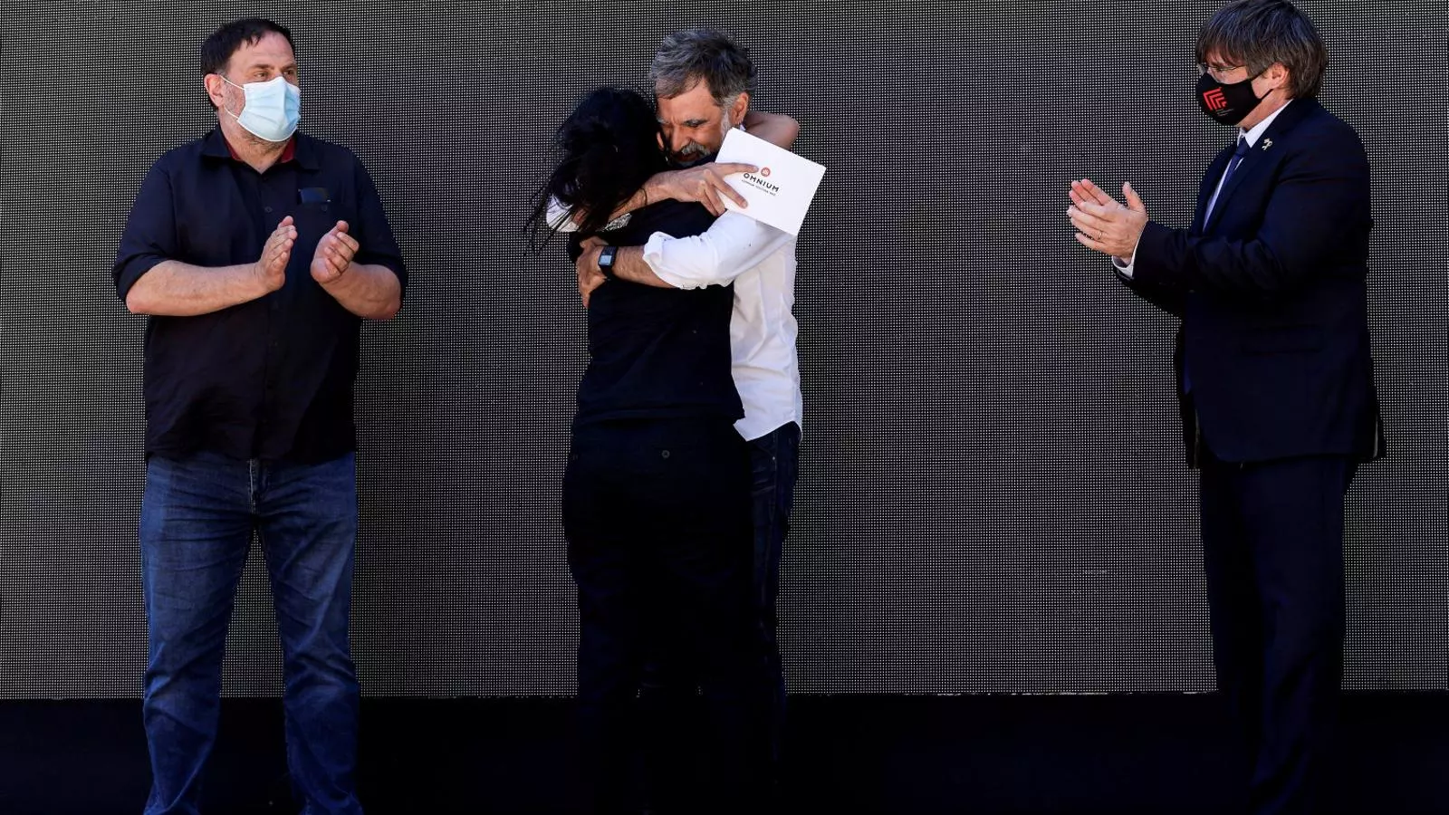 Jordi Cuixart i Anna Gabriel abraçant-se entre els aplaudiments d’Oriol Junqueras i Carles Puigdemont.