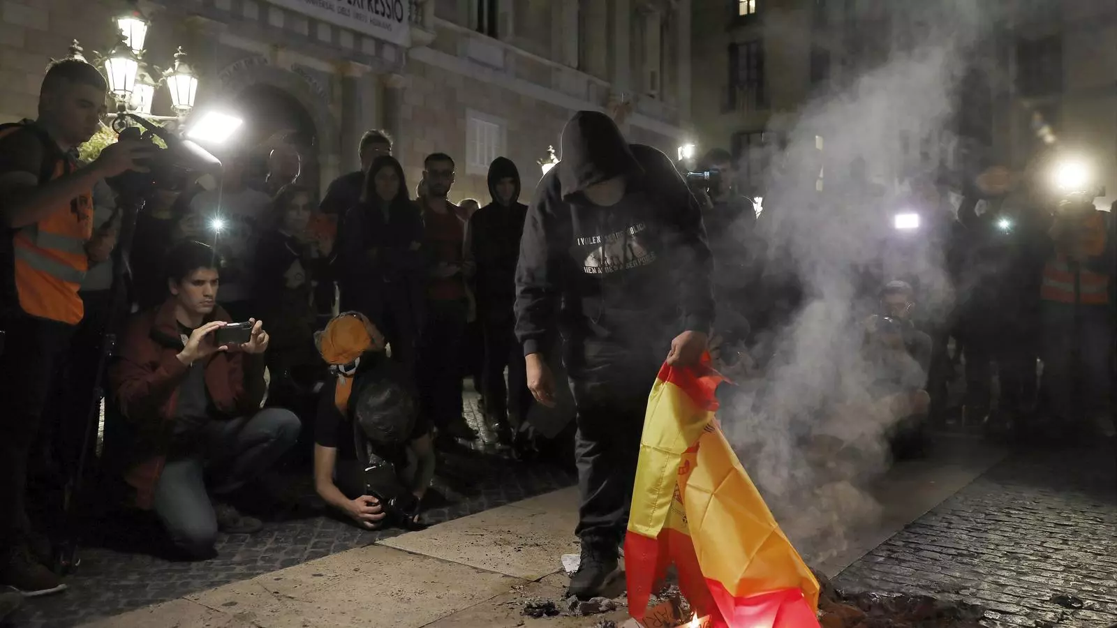 Un manifestant crema una bandera espanyola en una protesta a la plaça Sant Jaume de Barcelona