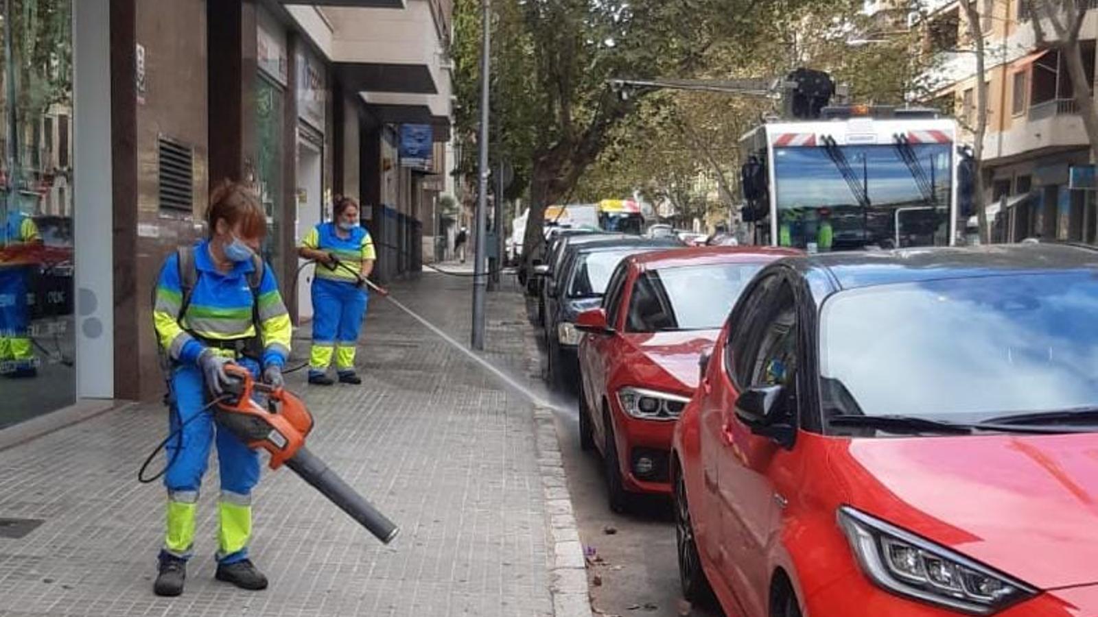 Dues operàries del servei de neteja d'Emaya amb aigua a pressió.