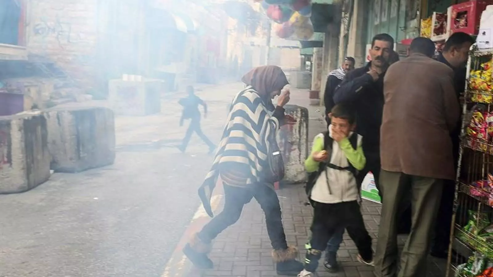Palestins intenten protegir-se d'un atac de gasos lacrimògens a la ciutat d'Hebron. ABED AL HASHLAMOUN / EFE