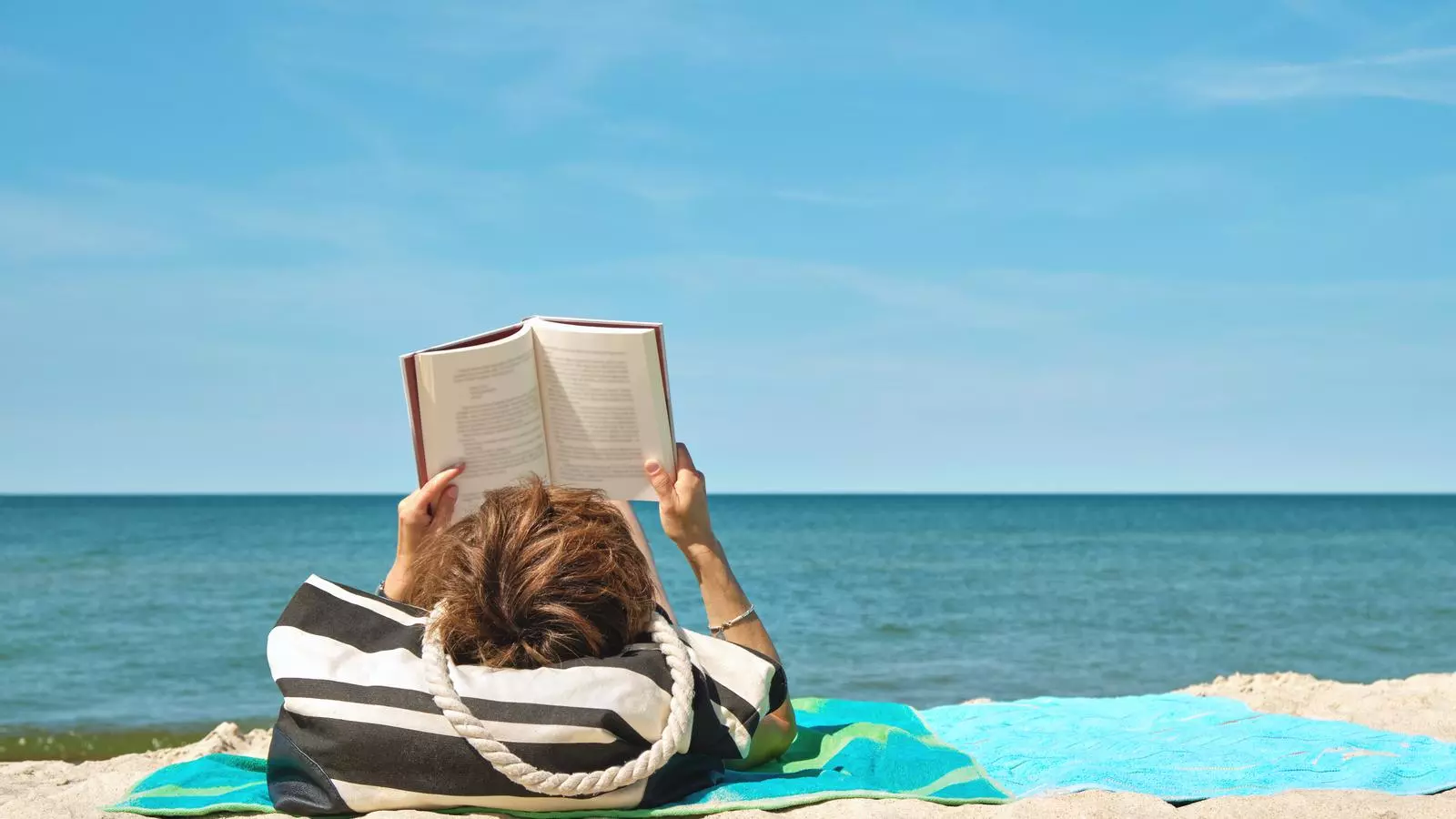 Una persona leyendo en la playa en una imagen de archivo
