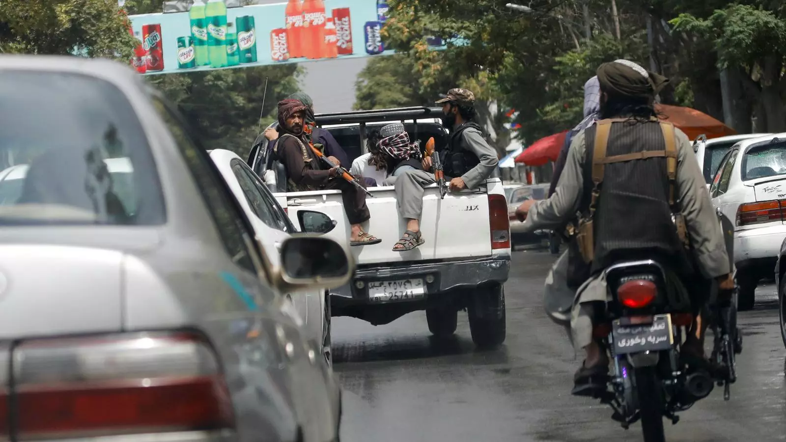 Dos talibans porten en una camioneta un home detingut en un carrer transitat de Kabul.