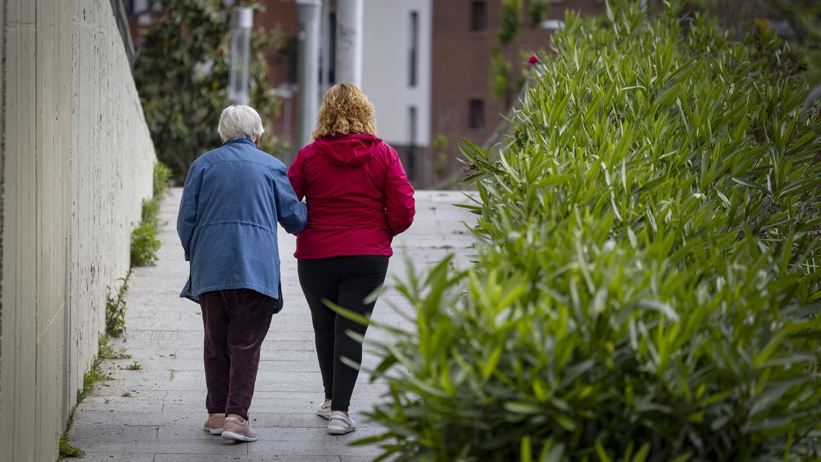 Una mujer mayor caminando al lado de otra, en el barrio barcelonés del Guinardó.