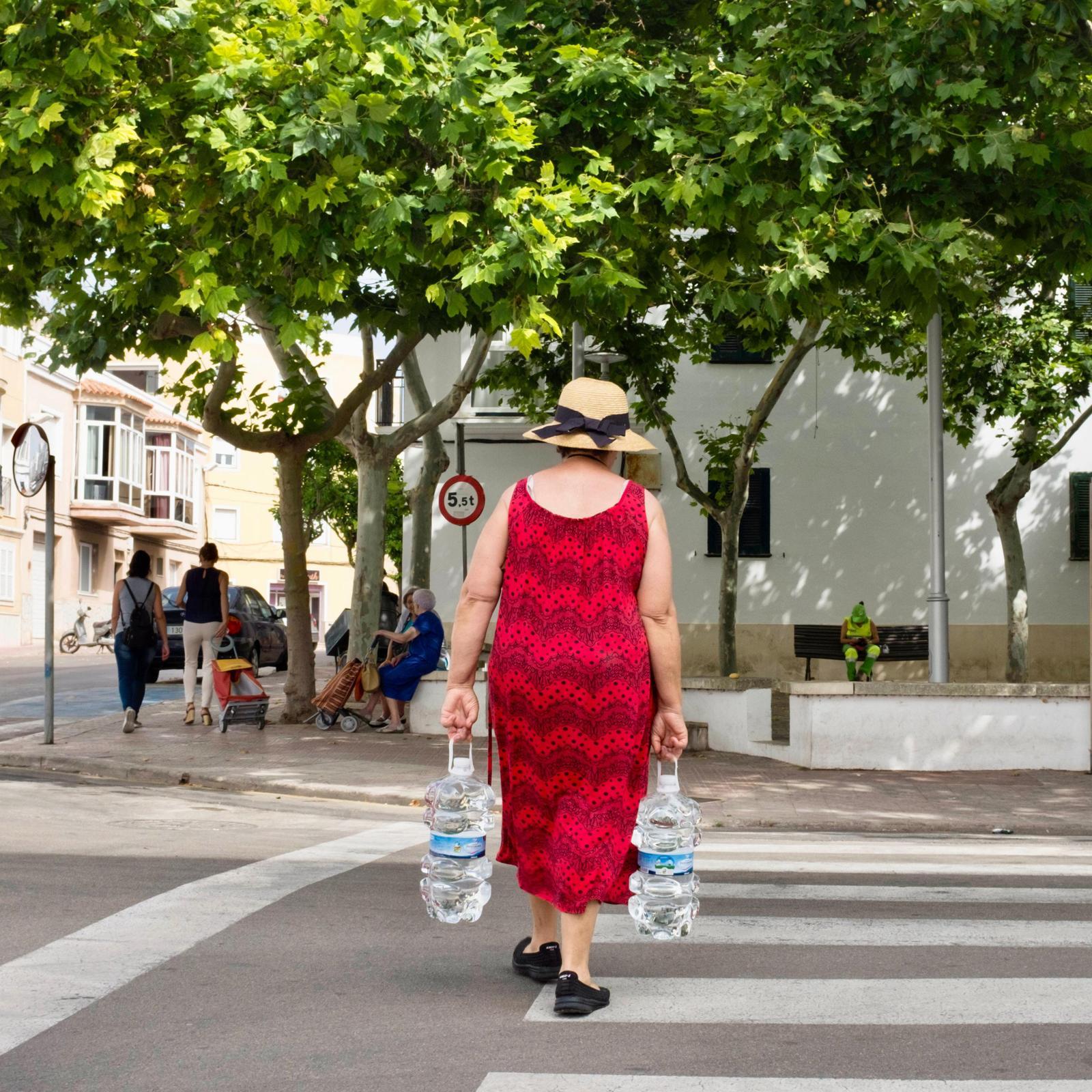 Una dona carrega garrafes d’aigua, carrer Sant Manuel de Maó