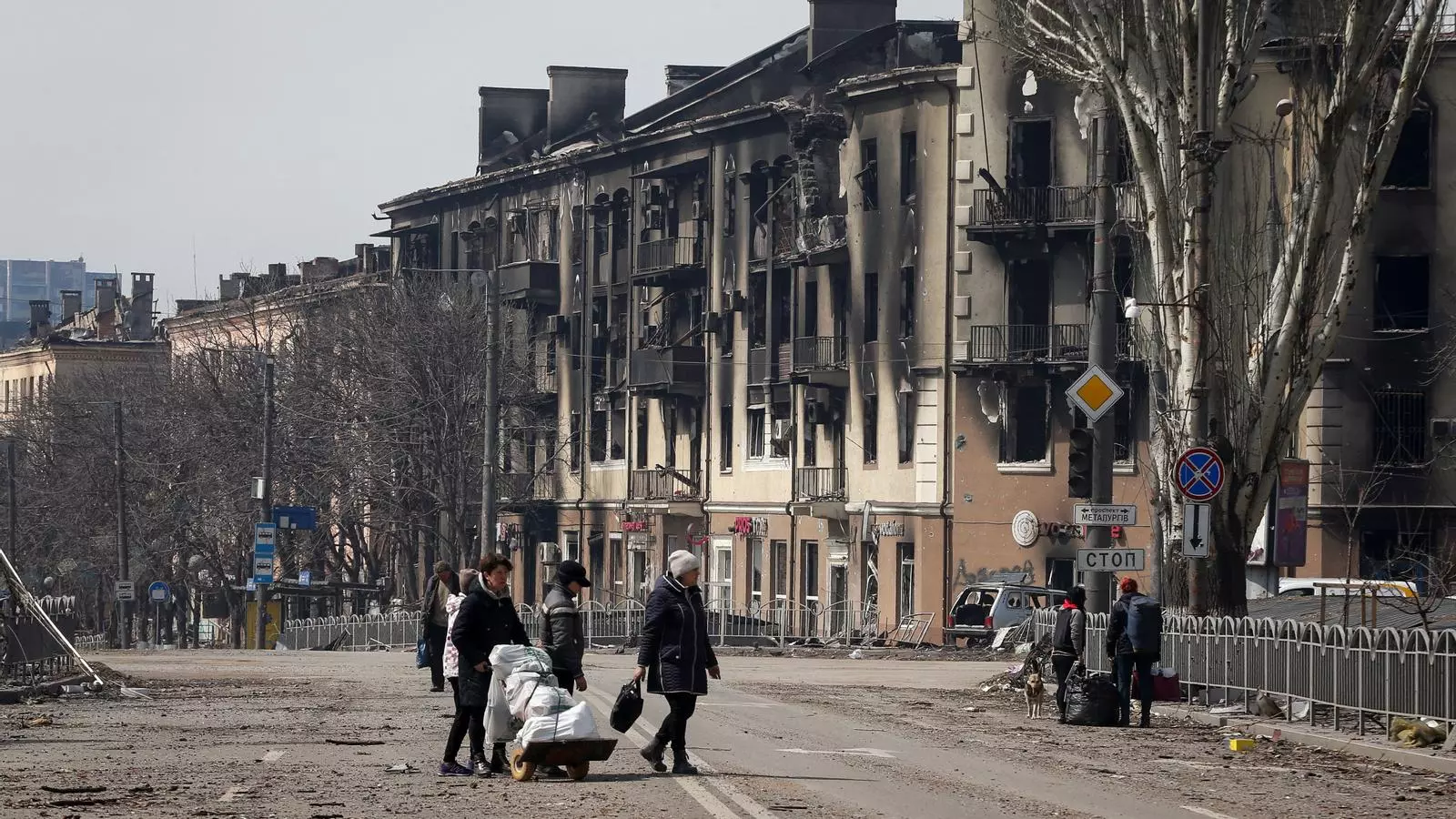 Residentes de la ciudad de Mariúpol cargan con sus pertenencias por las calles destruidas
