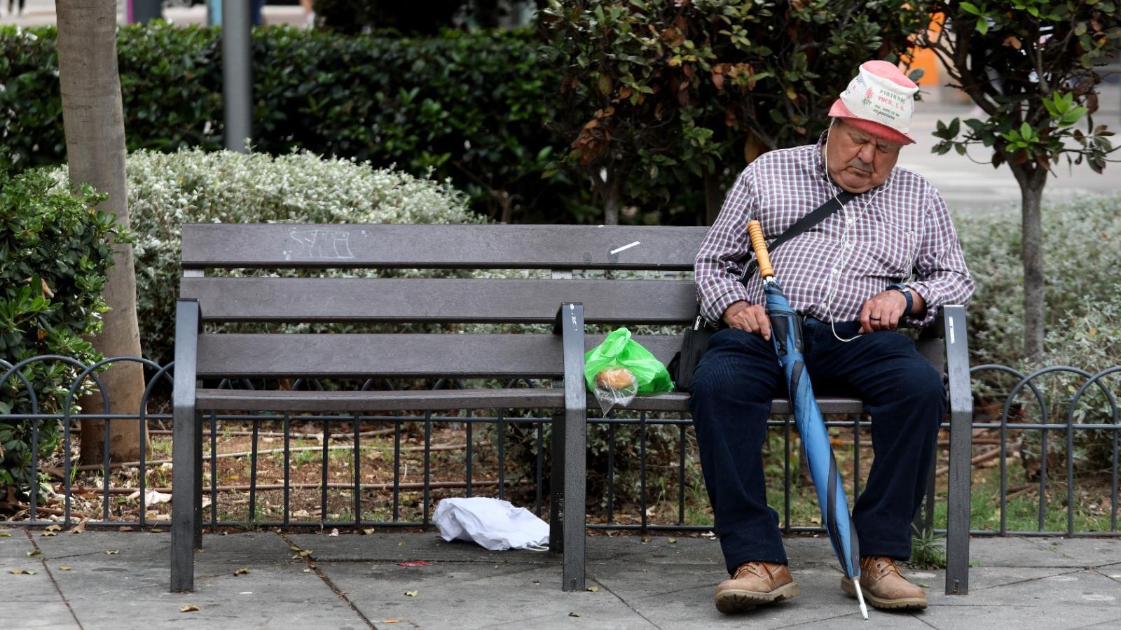 Un home gran assegut a un banc.