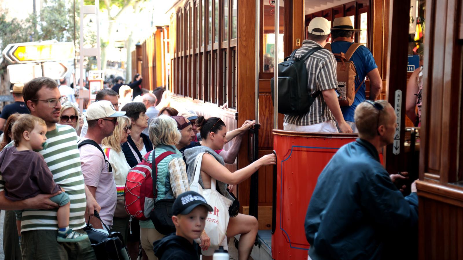 A group of tourists queues to be able to get on the Sóller train.