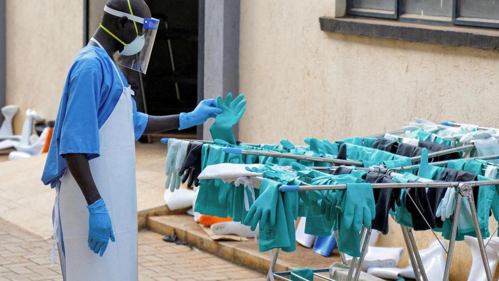 Un trabajador sanitario ugandés se acerca a un dispensador atestado de guantes.
