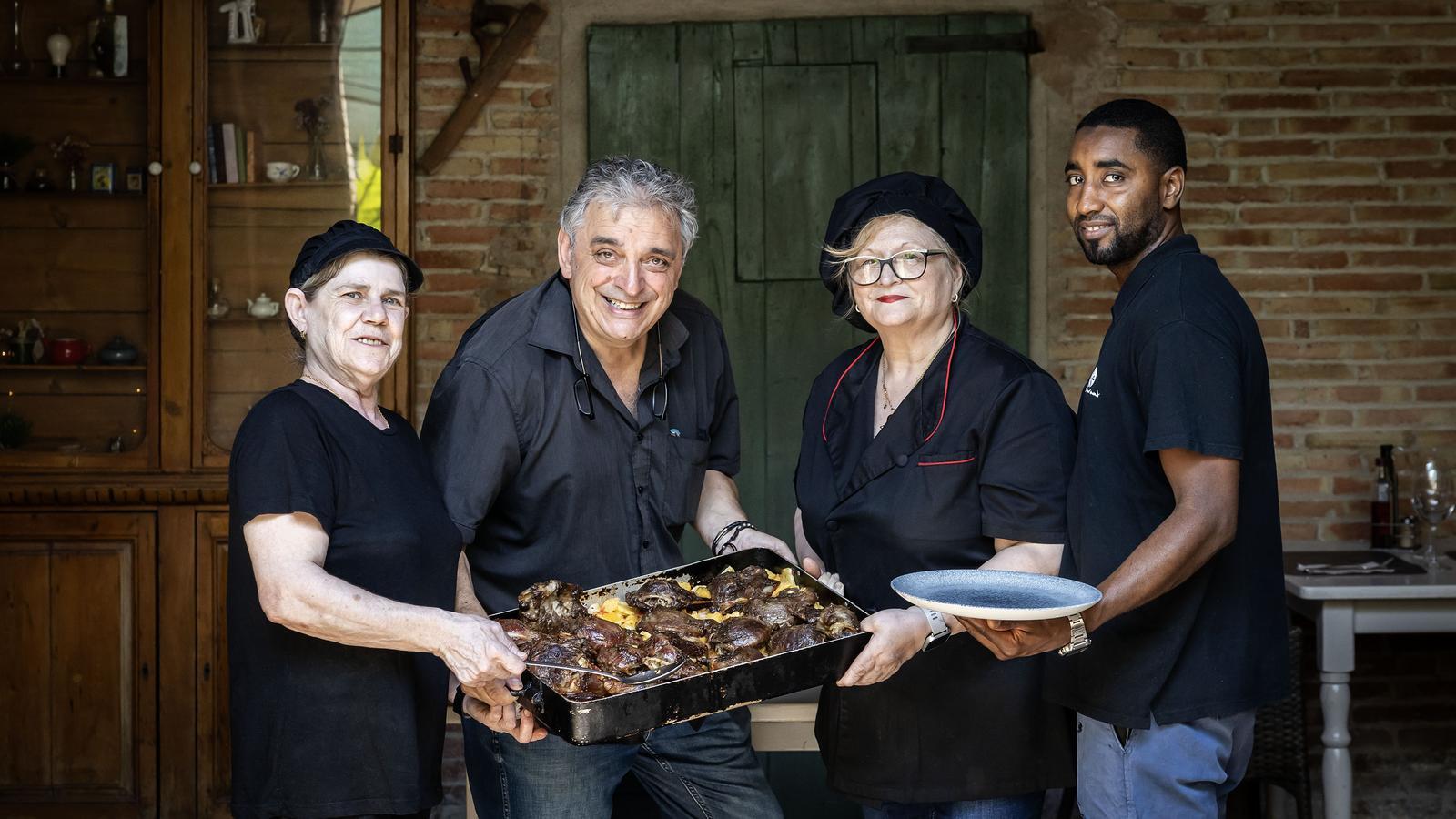 La Maricarme, el Jordi, la Anna Maria y el Hoggo con una bandeja de carrilleras de cerdo asadas.