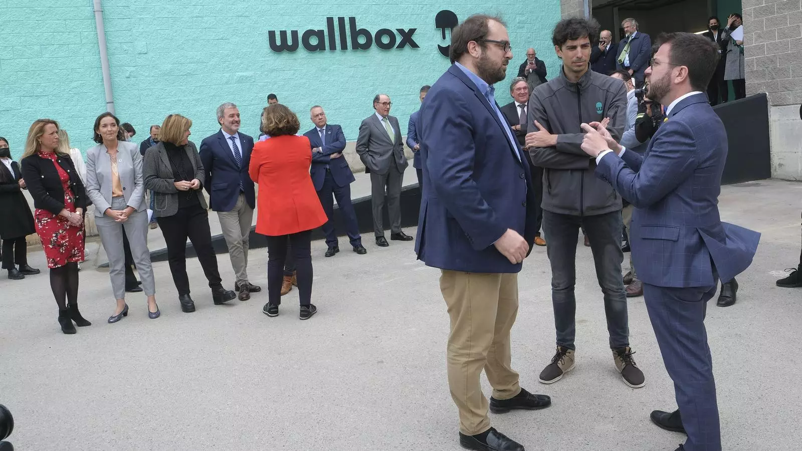 El president Pere Aragonès parla amb els fundadors de Wallbox amb la ministra Maroto i la resta d'autoritats al fons.