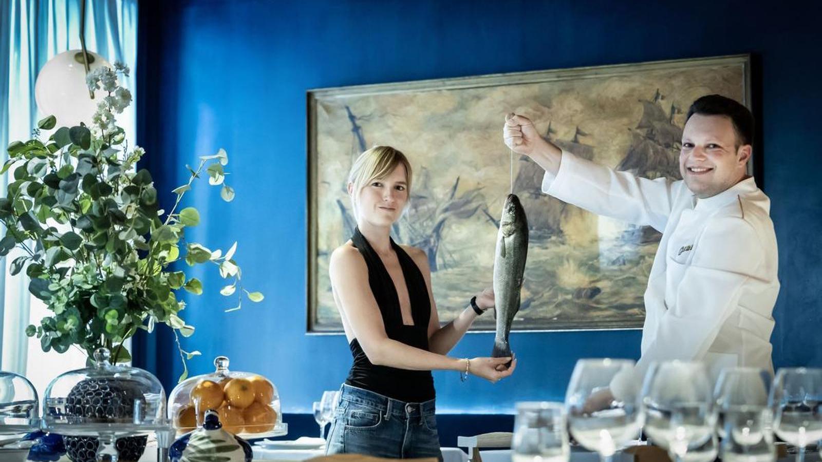 Alexia Iborra y Adria Barbera con una lubina en las manos en la sala del restaurante, en la calle Ginebra 15, de Barcelona
