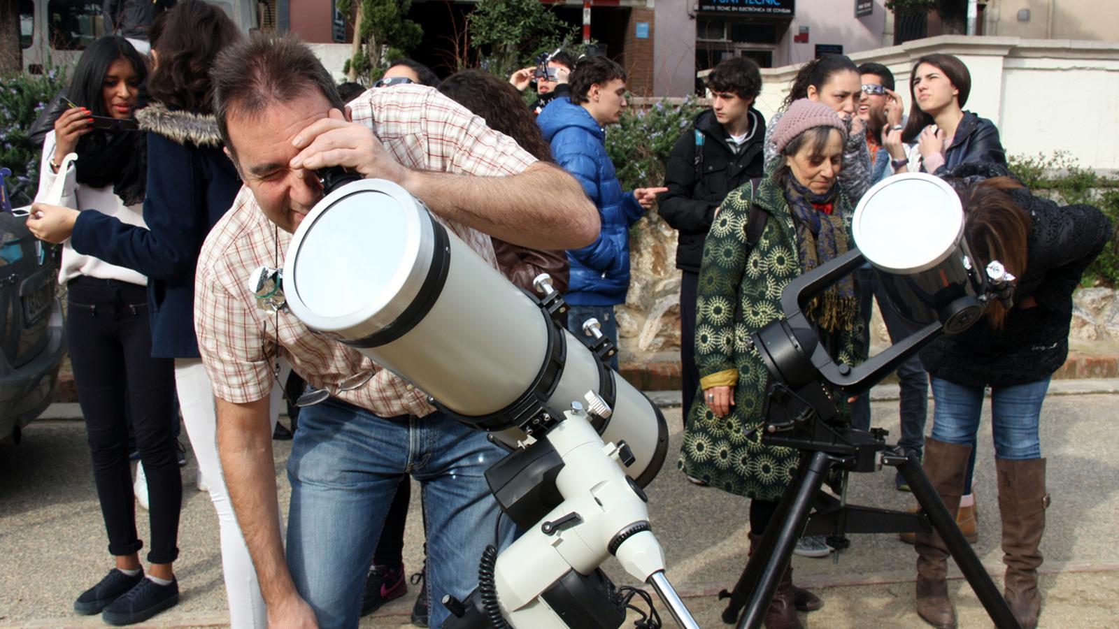 El president de la Societat d'Astrologia de Figueres, Pere Hors, amb els telescopis que han muntat davant l'IES Muntaner / ACN