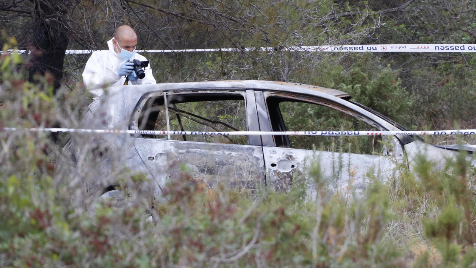 Un investigador dels Mossos fotografiant el cotxe calcinat on s'ha trobat el cadàver.