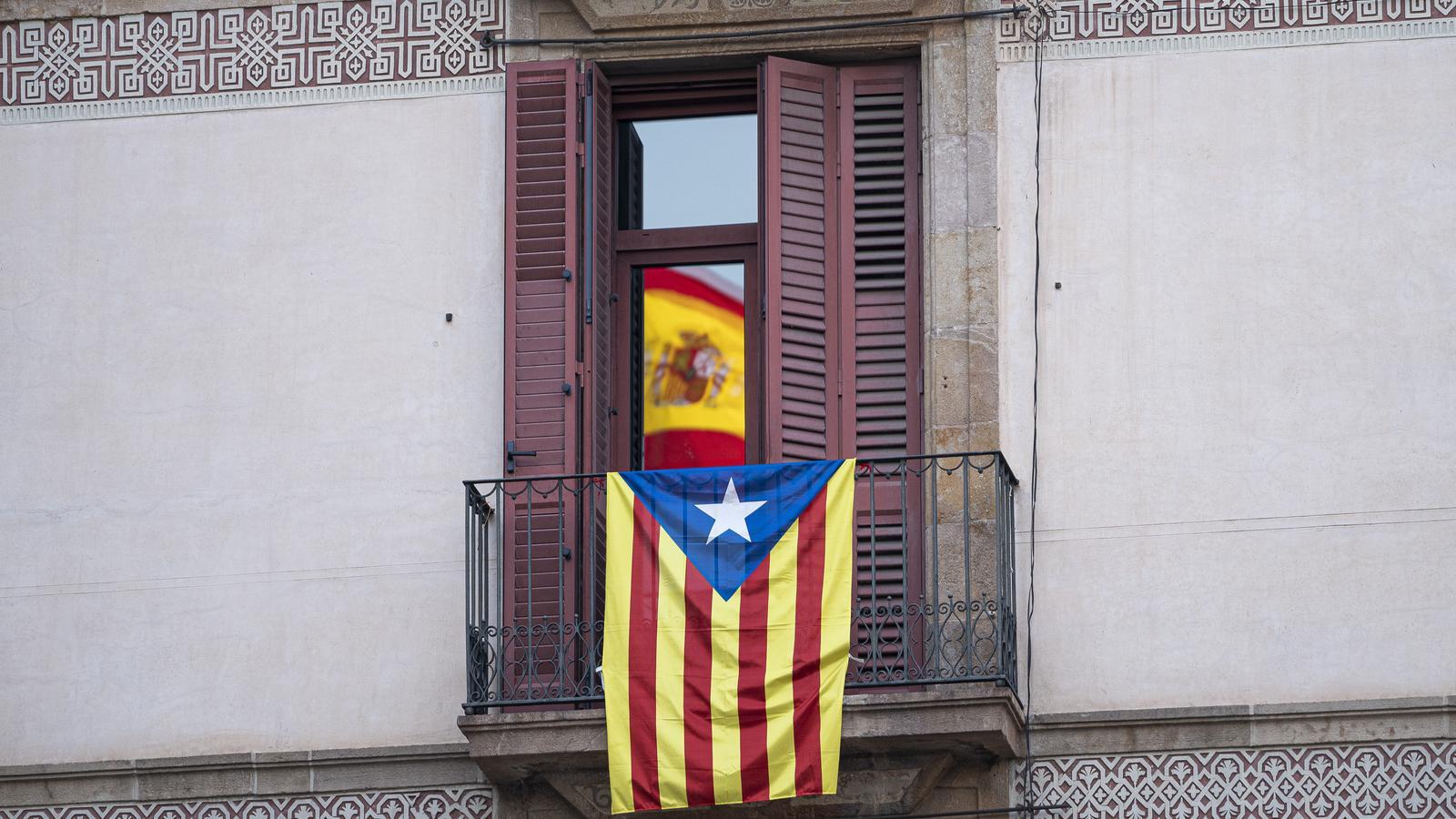 Una estelada a un balco d'un pis de la Plaça Sant Jaume i el reflex d'una bandera d'Espanya del Palau de la Generalitat.