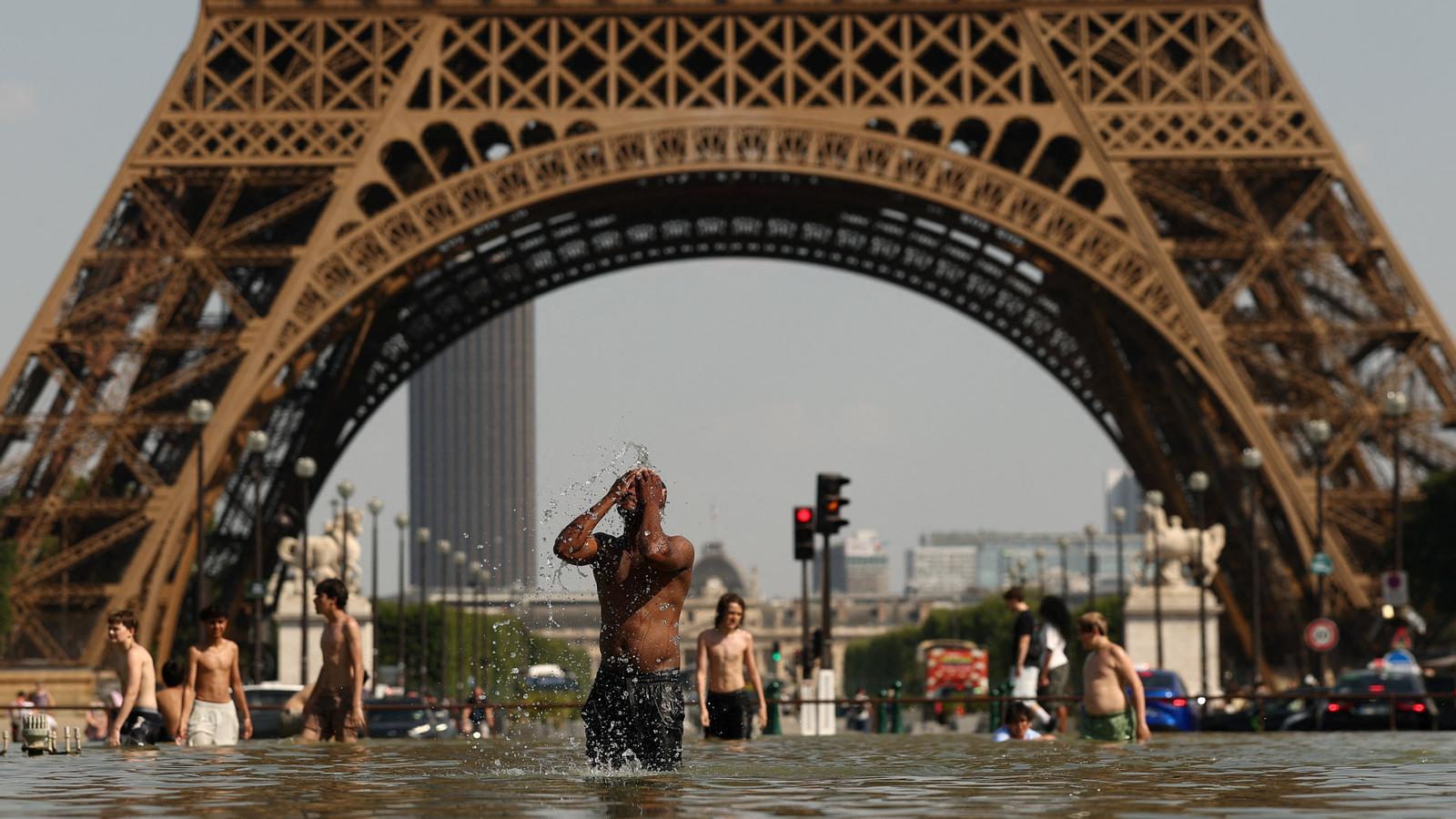 La gente se refresca en la fuente del Trocadero, delante de la Torre Eiffel de París, en una ola de calor histórica en Francia