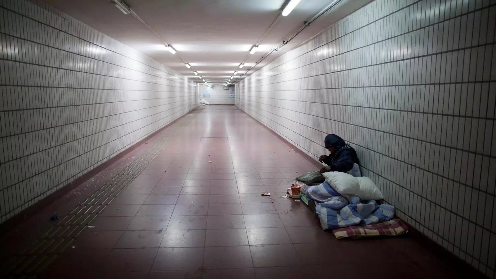 Un home sense llar a l'entrada del metro.