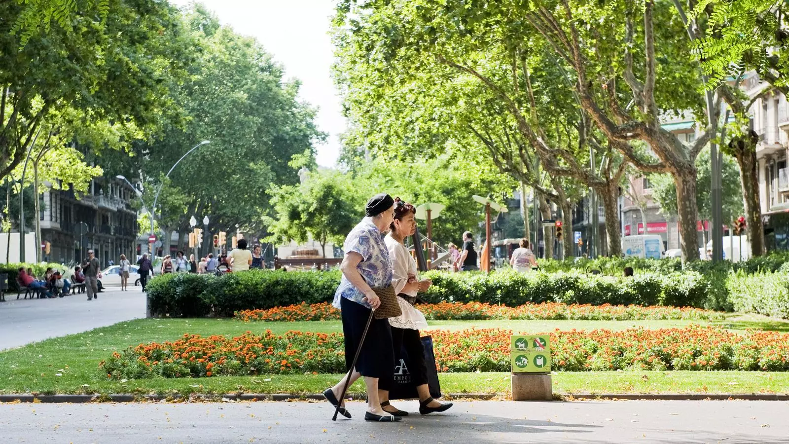 Una cuidadora passejant amb una senyora gran per la rambla del Passeig Sant Joan