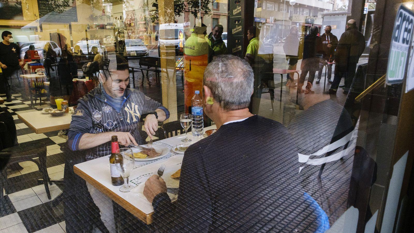 Clients a l'interior d'un restaurant amb el reflex de la terrassa exterior.