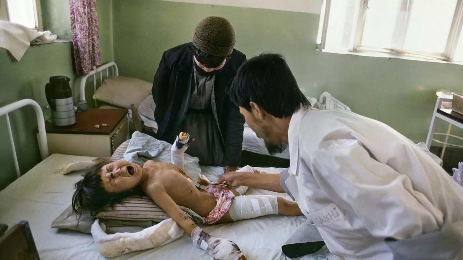 Fàtima llama y se recargola de dolor en un hospital de Kabul mientras un sanitario le cura las heridas.