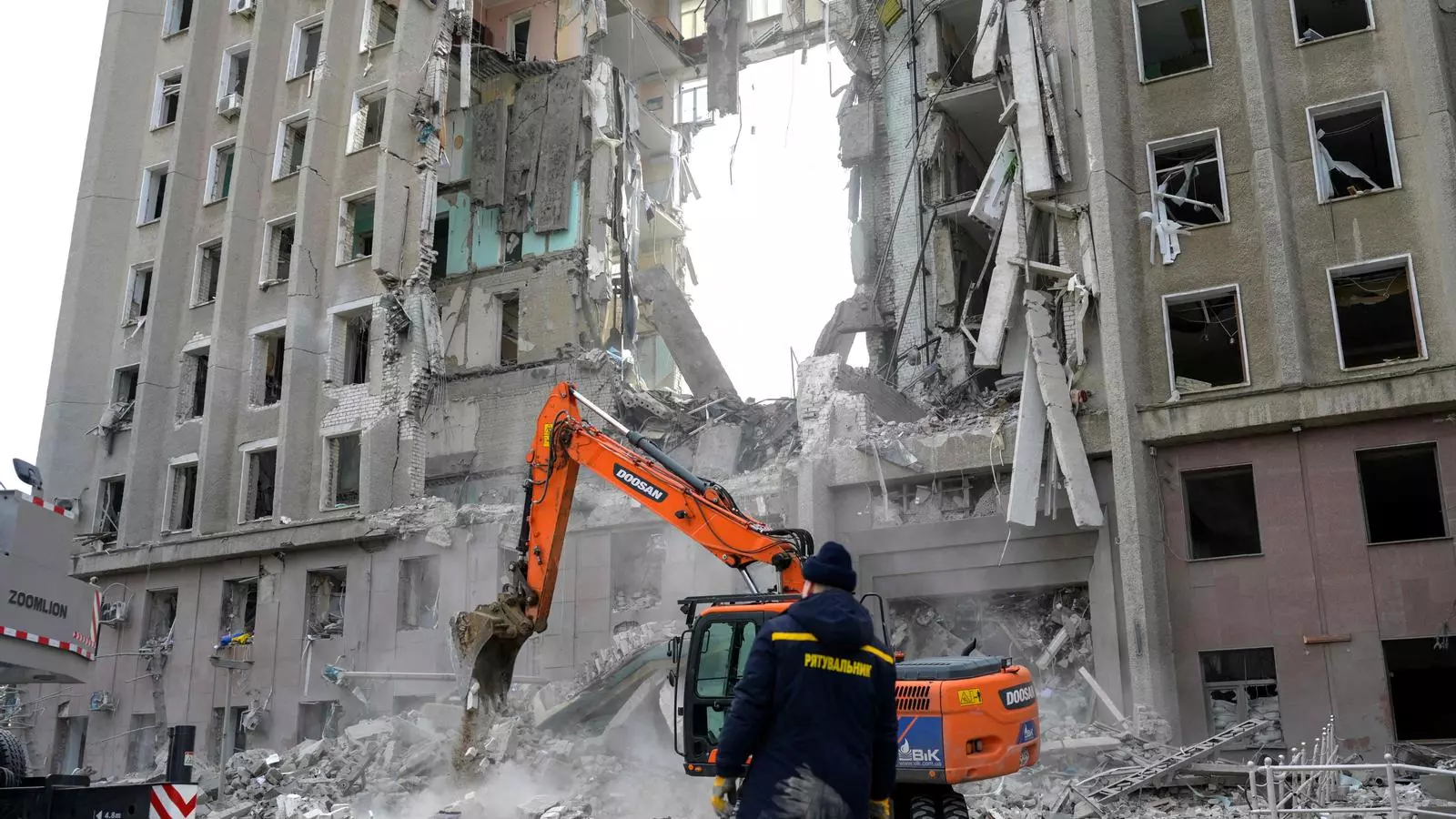 Un treballador observa com una excavadora neteja els enderrocs d'un edifici governamental colpejat per coets russos a Mykolaiv