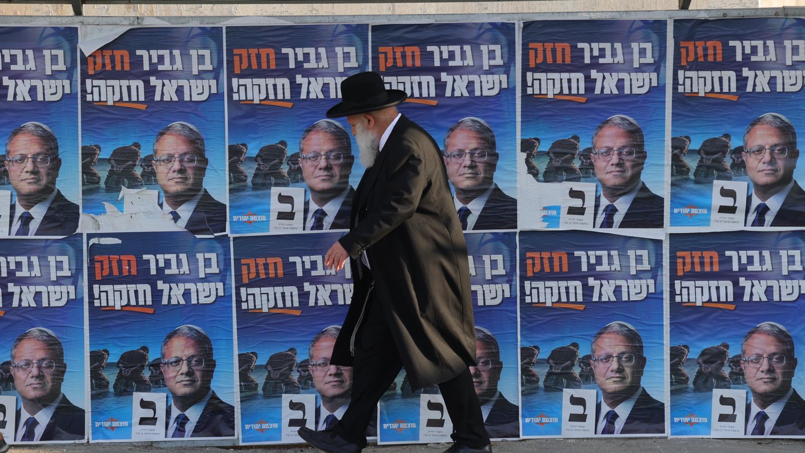 An ultra-Orthodox Jew in Jerusalem, in front of election posters of the Minister of National Security and leader of the Otzma Yehudit party, Itamar Ben-Gvir.