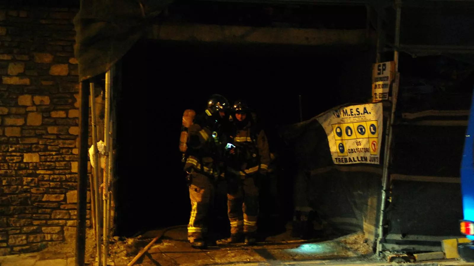 Dos bombers s'introdueixen a l'edifici en obres per apagar l'incendi