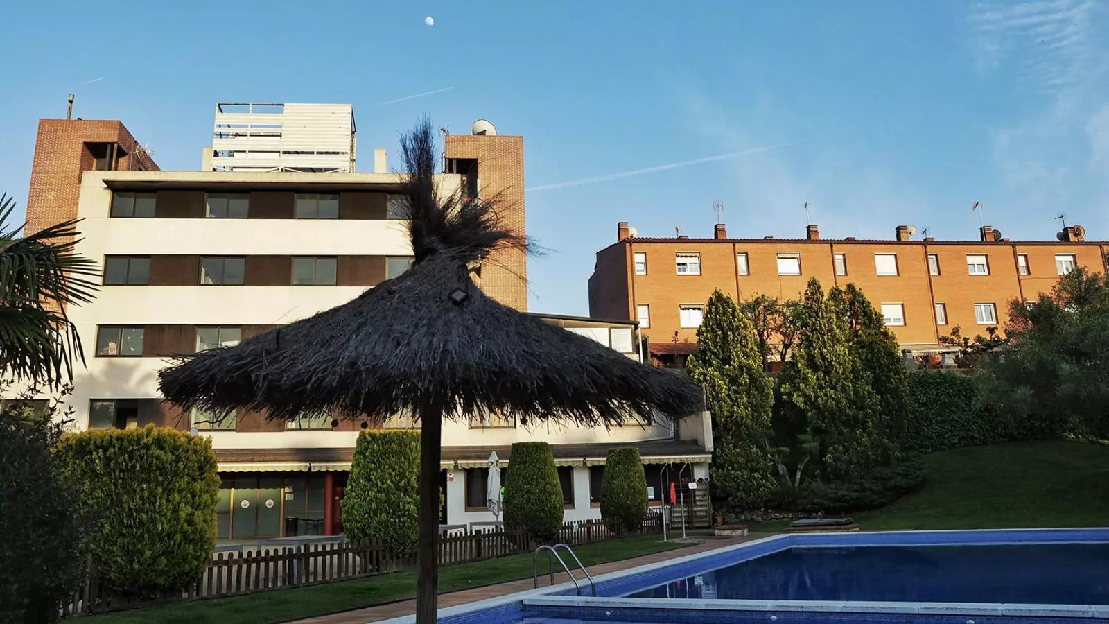 L’edifici de l’antic hotel (a l’esquerra) on s’han de traslladar els menors comunica amb un espai comunitari amb piscina dels veïns.