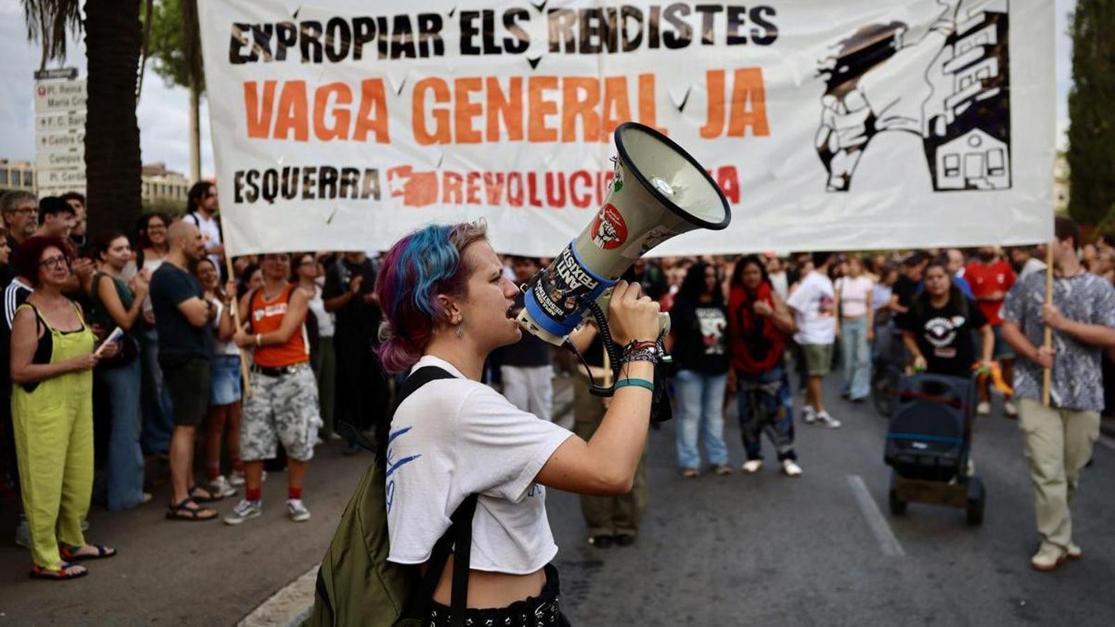 A protester shouts with a megaphone at the protest on the Diagonal of Barcelona to demand solutions to the housing crisis, in front of a banner in favor of the general strike.