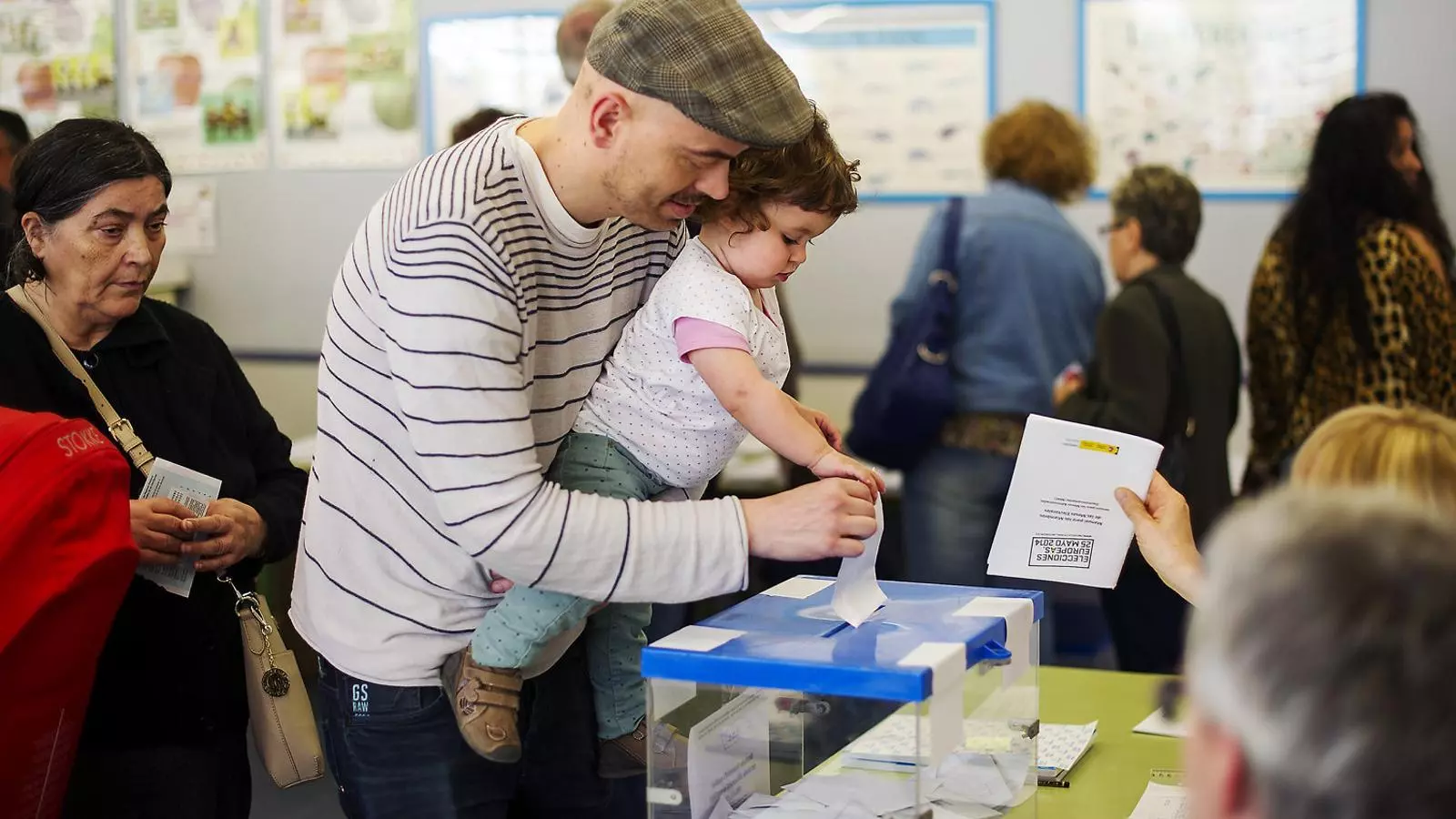 Un home amb una nena als braços diposita una papereta dins una urna a les eleccions europees del maig del 2014.