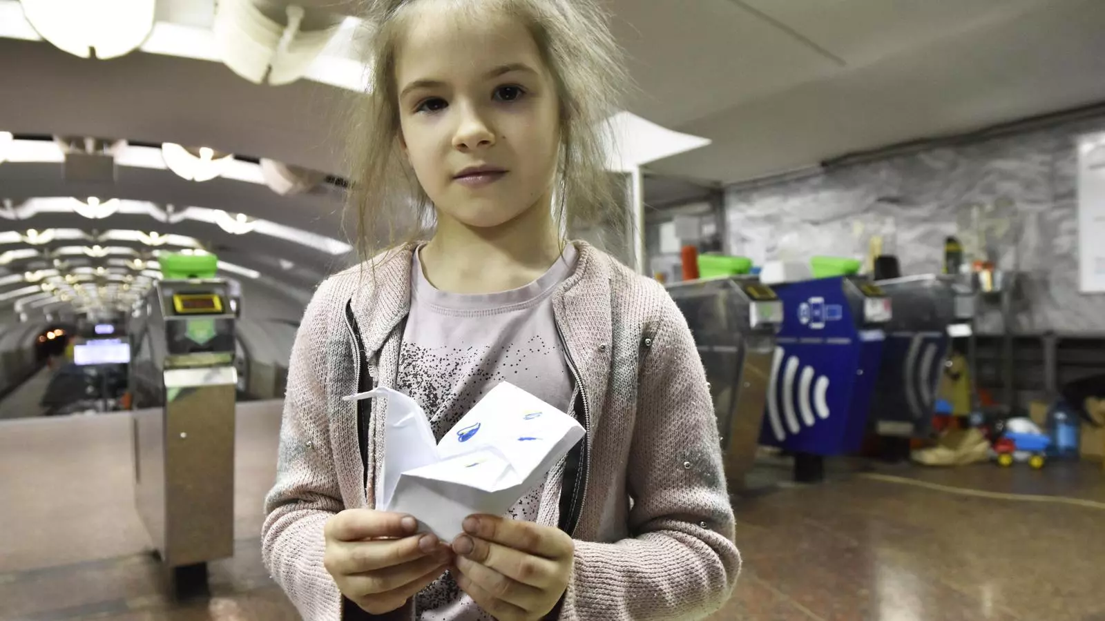 La Mira, de 8 anys, ensenya el colom de la pau que ha fet amb un tros de paper a l'estació de metro de Khàrkiv.
