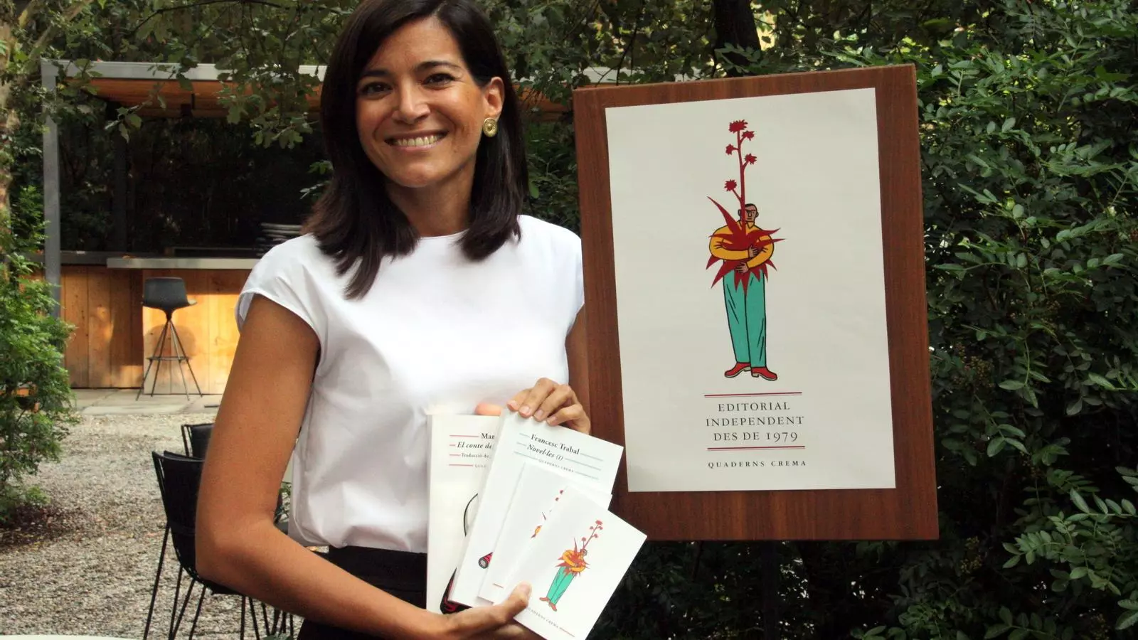 L'editora de Quaderns Crema, Sandra Ollo, al costat del nou cartell que il·lustra la nova etapa de l'editorial