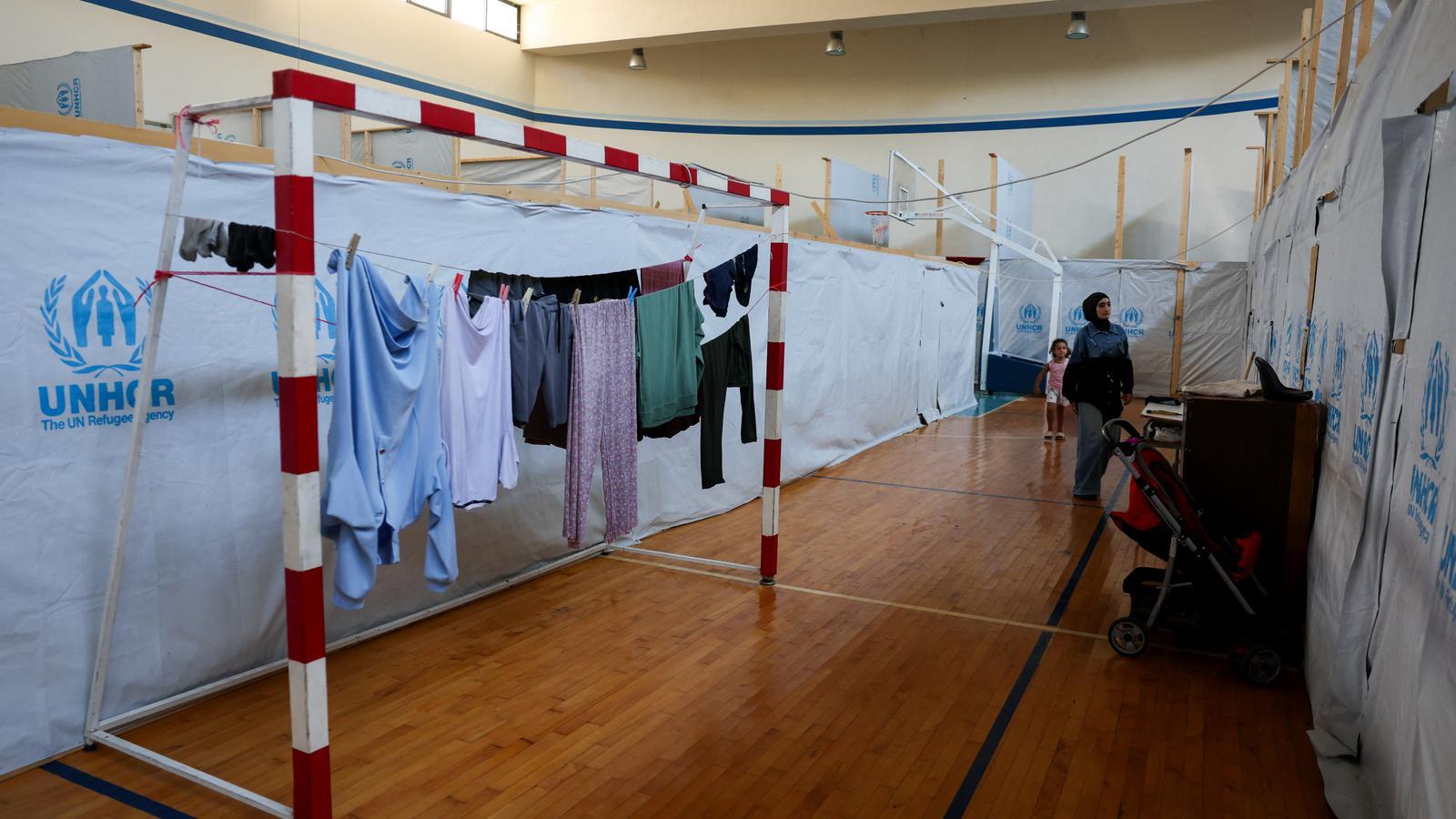 Una mujer y un niño caminan por la pista deportiva, rodeada de tiendas, de una escuela convertida en refugio para familias desplazadas en Tiro, en el sur del Líbano.