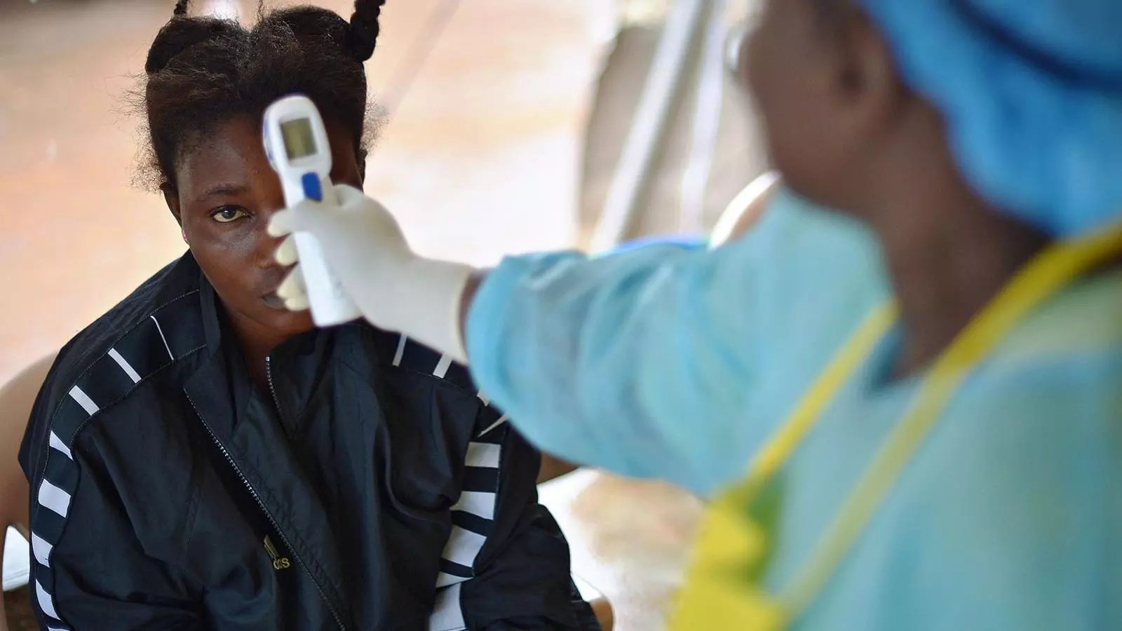 Una infermera prenent la temperatura a una noia que presenta símptomes d’Ebola.