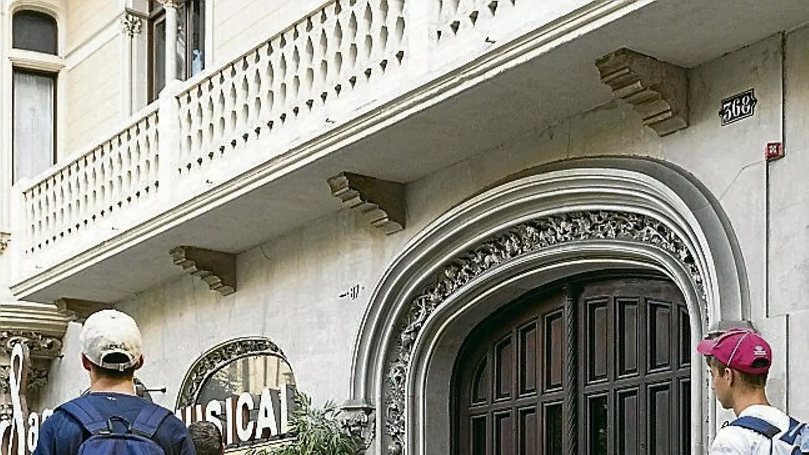 Turistes a la porta de l’edifici del passeig Sant Joan on hi ha els pisos turístics il·legals.
