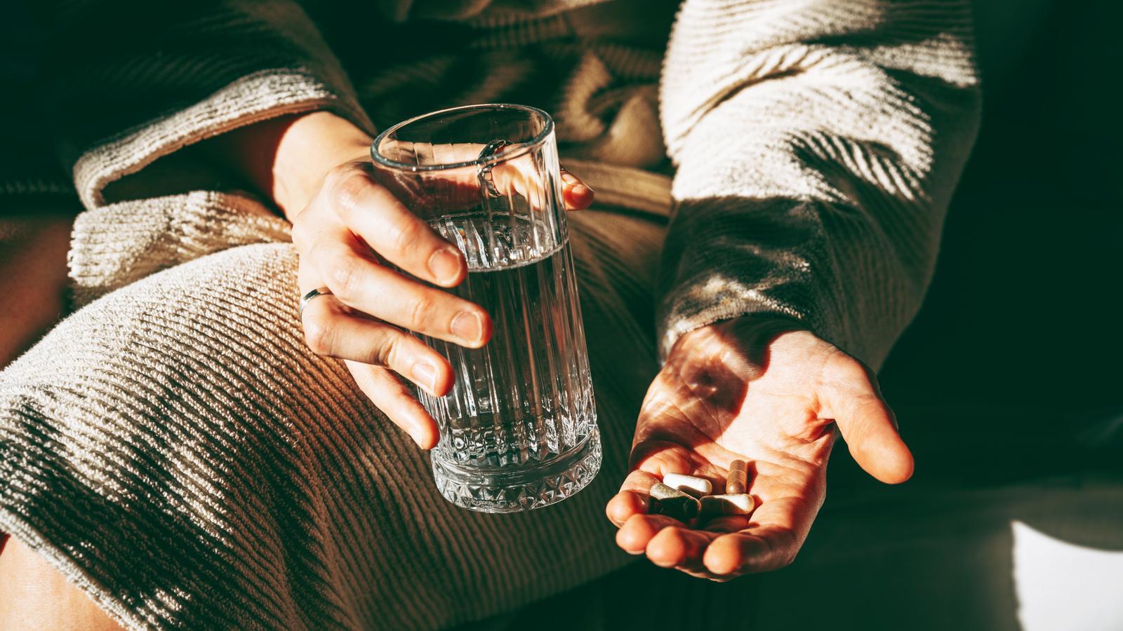 Una mujer con un puñado de pastillas homeopáticas