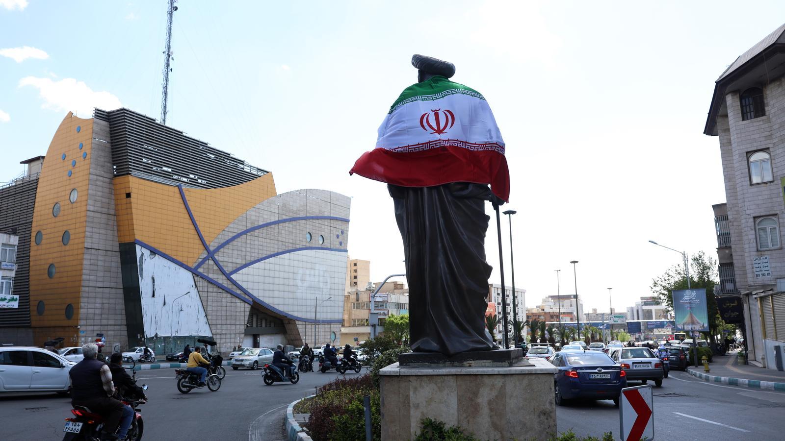 La bandera nacional de Irán envuelve una estatua en Teherán, después del anuncio de una tregua de dos semanas con los EE. UU.