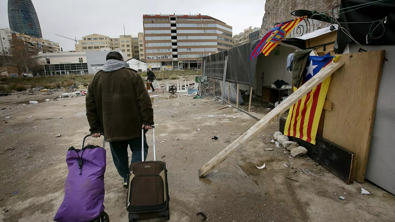 El Doro, un home romanès, arribant carregat de maletes a la seva barraca, en un solar situat al costat de la plaça de les Glòries.