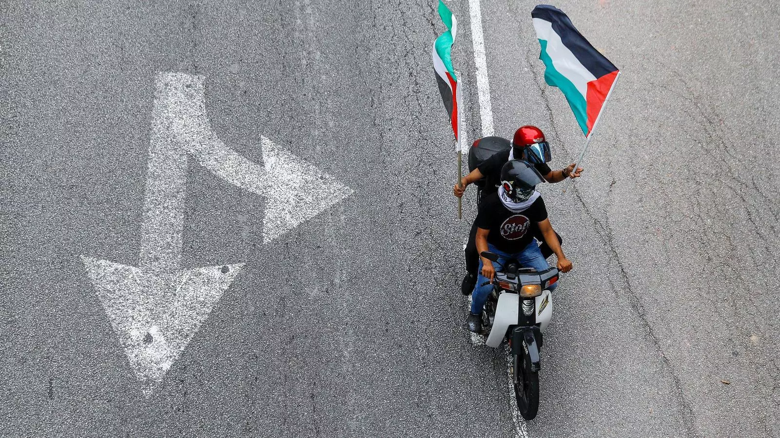 Dues persones amb motocicleta onejen banderes palestines.
