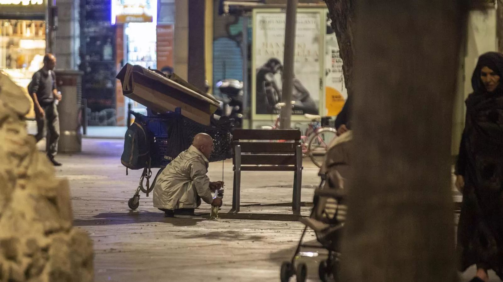 Un home que dorm al carrer carregant amb les seves pertinences al centre de Barcelona