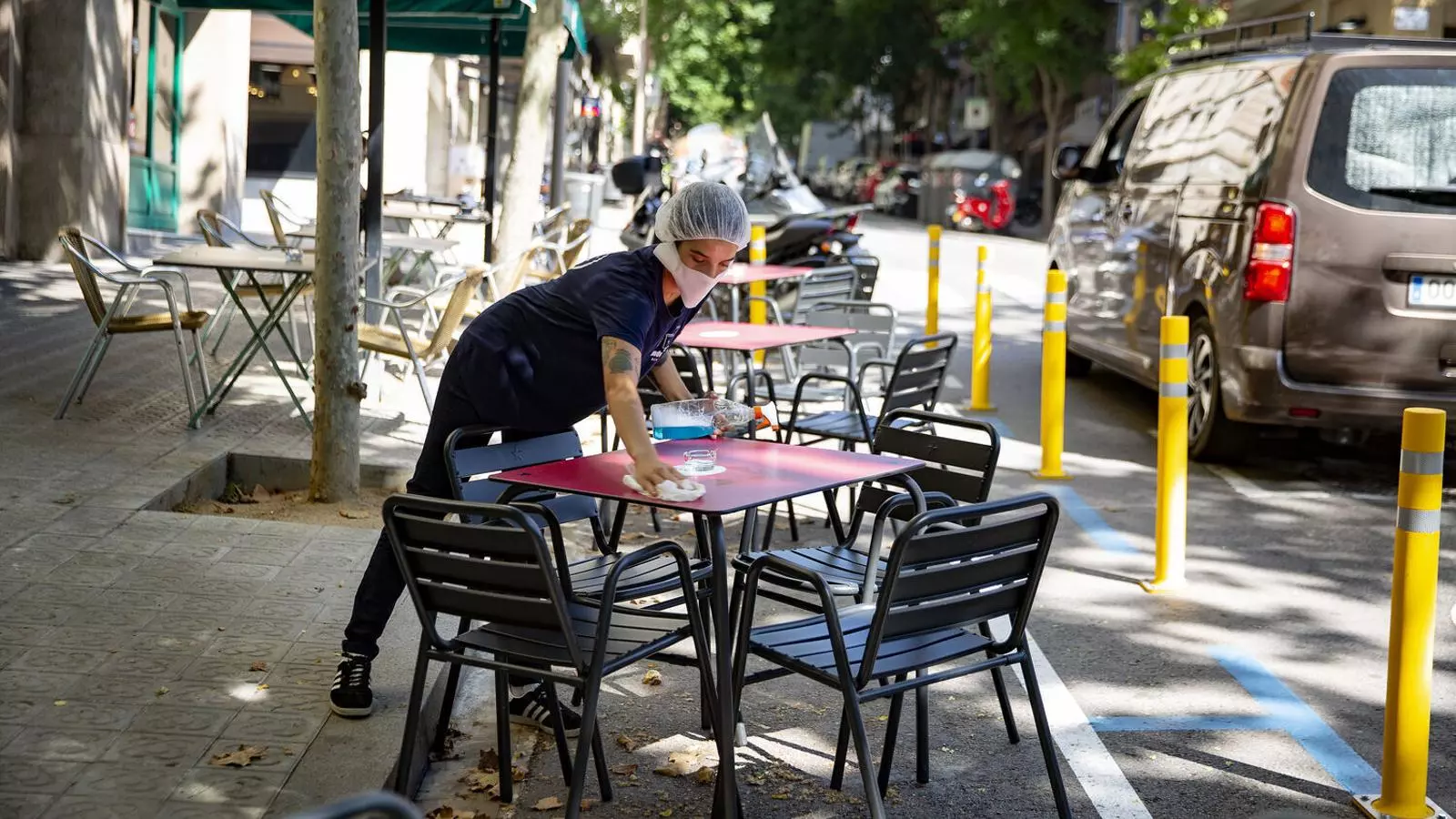 Una cambrera recollint la taula de la terrassa d'un bar de Barcelona durant la pandèmia del covid-19. / FRANCESC MELCION