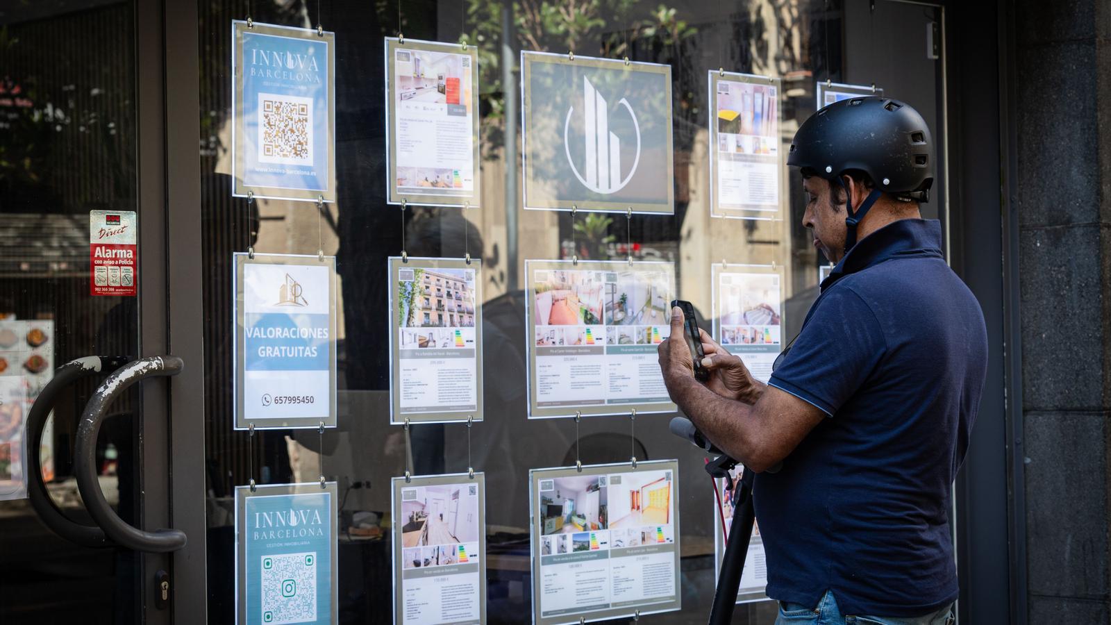 Un hombre mirando pisos en una inmobiliaria de Barcelona.