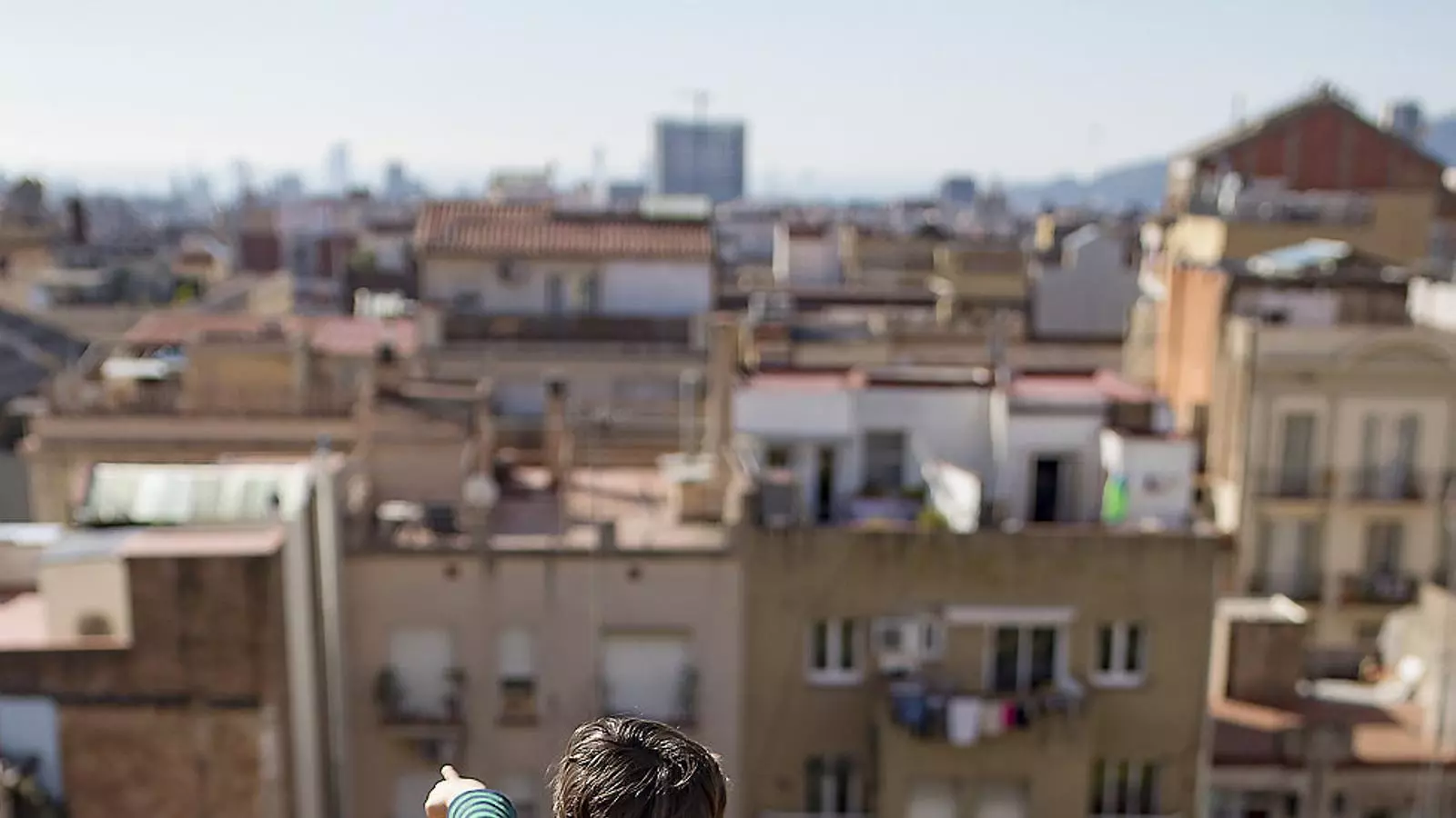 Un nen mirant la ciutat des del terrat de casa.