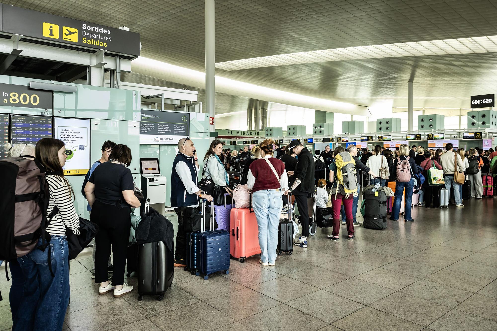 Passatgers fent cua per facturar les maletes a la T1 de l'aeroport del Prat.