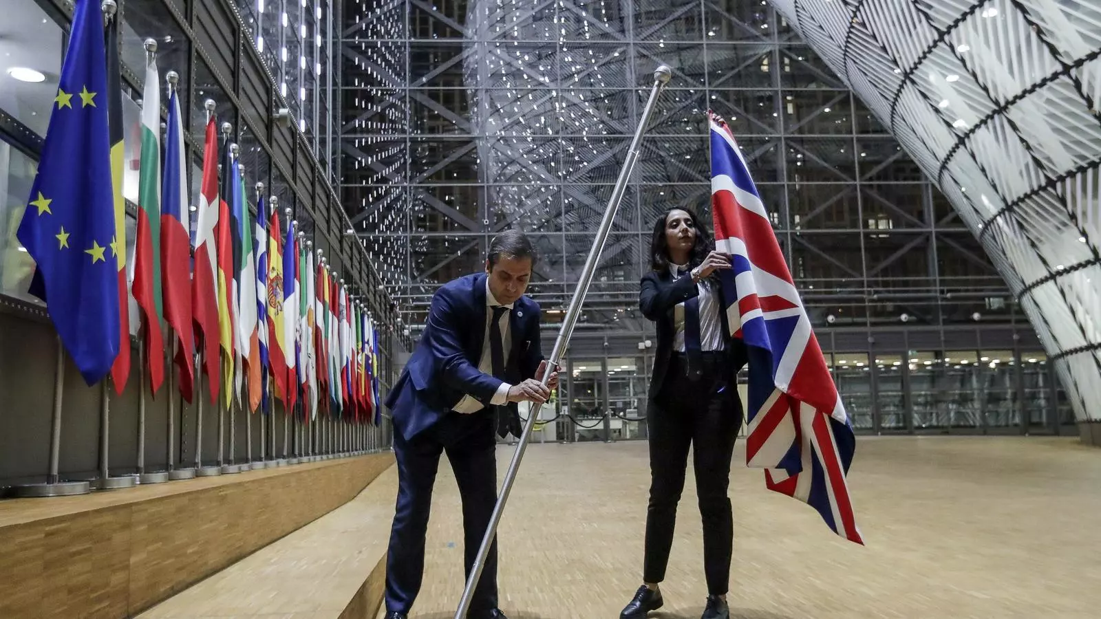 Dos treballadors retiren la bandera de l'interior de l'edifici del Parlament Europeu